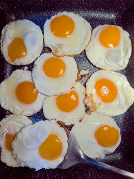Flat lay of fried eggs in a pan with a spatula