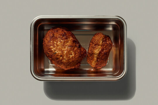 Still life view from above of two meatballs in stainless steel container