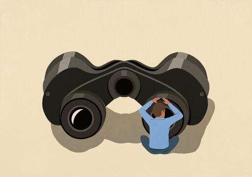 Curious man looking through large binoculars on yellow background
