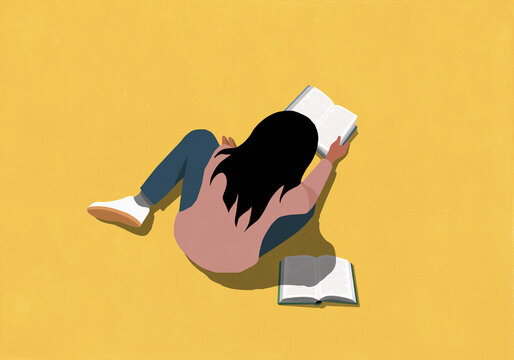 High angle view of girl reading book on yellow background