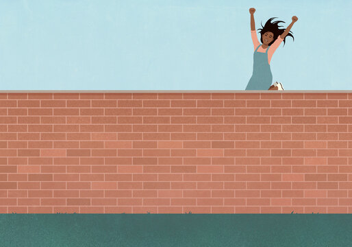 Carefree young woman jumping for joy above brick wall