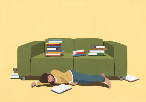 Tired girl surrounded by books, taking a break from studying and sleeping on floor below green sofa