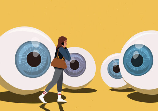 Large eyeballs watching young woman talking on mobile phone against yellow background