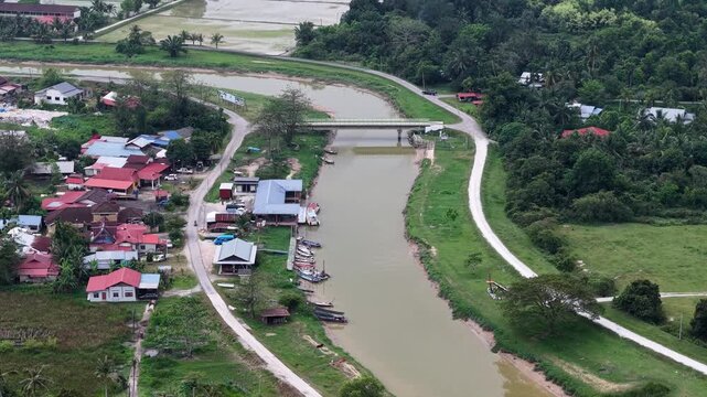 Aerial drone shot of Labuh Banting Malays village showing river, bridge, boats, houses and vegetation.