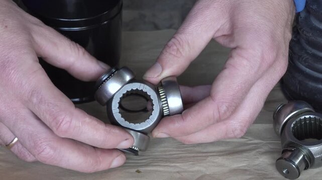 Auto mechanic inspects new internal CV joint tripod, Mechanic holds three-way CV joint bearing for replacement