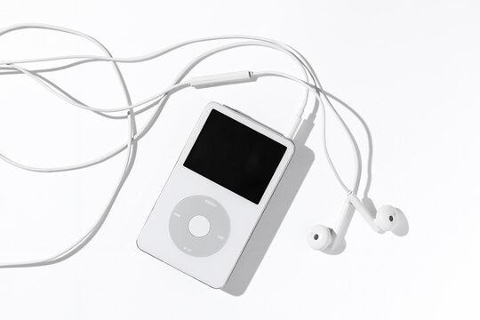 Bangkok, Thailand - May 3, 2026: An iconic white Apple iPod Classic music player connected to original wired headphones on a plain white surface.
