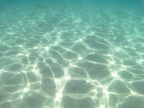 Underwater split view of crystal clear turquoise sea water with sandy bottom