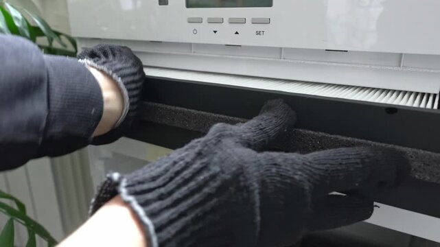 A worker wearing gloves is fitting a new air filter into the air filtration system.
