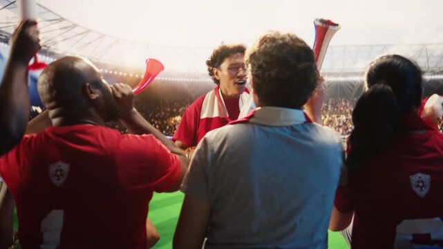 Enthusiastic man in stadium beating drum, encouraging team and creating loud match day energy, showing players, showing football fan leader galvanizing red shirt supporters in live sports arena.