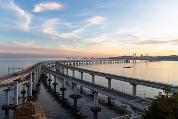 Fototapeta premium Kuahai Bridge View Point, spectacular double-deck suspension bridge. Stunning panoramic views of the sea, making it one of Dalian's best places for sightseeing. Bridge curving over calm sea at sunset.