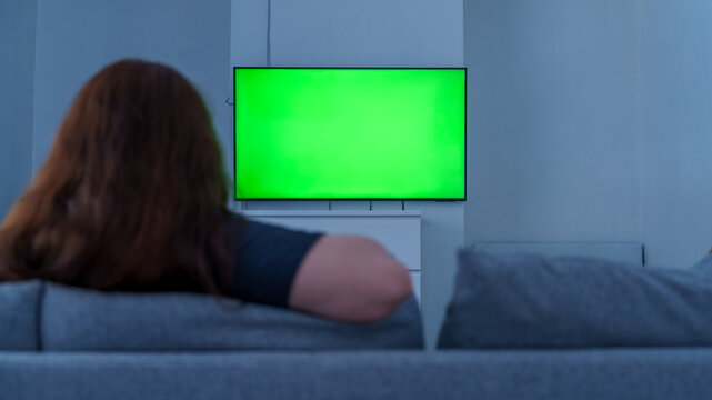 Woman watching a green screen tv at home