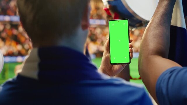 Close up of mockup phone used by fan in stadium to compare odds during soccer match day for sports betting, editable screen and fan reaction content.