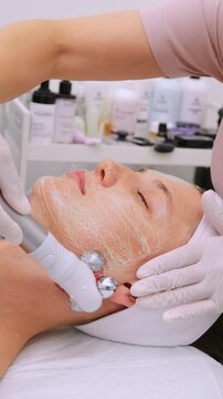 Relaxed young woman receiving an innovative hardware cosmetology procedure with a microcurrent facial toning device to stimulate muscles and reduce puffiness for a lifting and anti-aging effect
