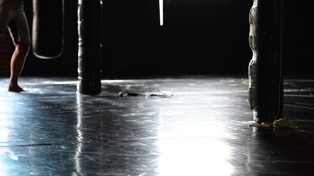 Dark lit gym boxing, martial arts, man working out, kickboxing, mat space, cinematic in silhouette bokeh background video, martial arts Wellnes theme