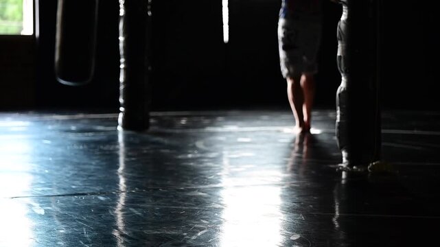 Dark lit gym boxing, martial arts, man working out, kickboxing, mat space, cinematic in silhouette bokeh background video, martial arts Wellnes theme
