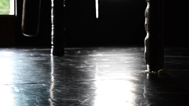 Dark lit gym boxing, martial arts, empty gym bag swinging in slow motion, kickboxing, mat space, cinematic in silhouette bokeh background video, martial arts Wellnes theme