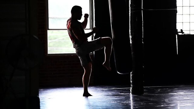 Dark lit gym boxing, martial arts, man working out, kickboxing, mat space, cinematic in silhouette bokeh background video, martial arts Wellnes theme