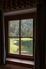 Fototapeta premium Cozy Wooden Window with Scenic Lake and Forest View in the Alps