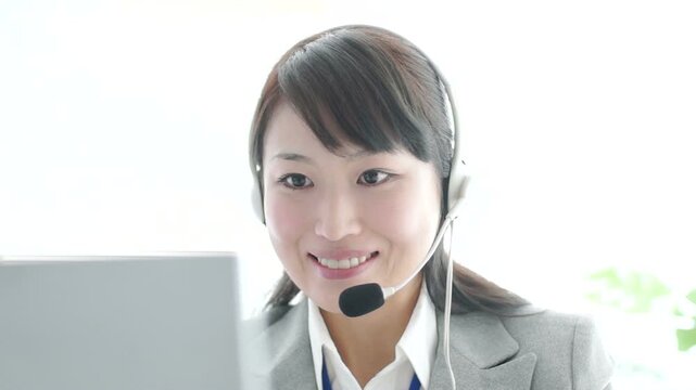パソコンに向かいインカムで電話対応する日本人女性