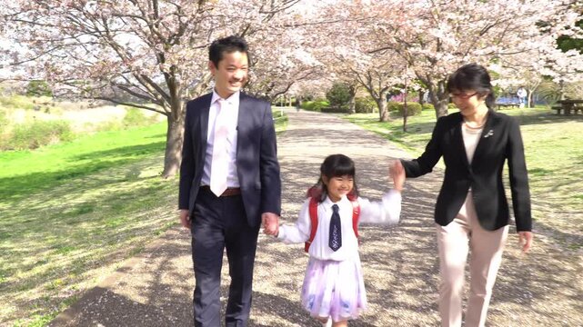 両親と手をつないで歩く小学一年生の女の子