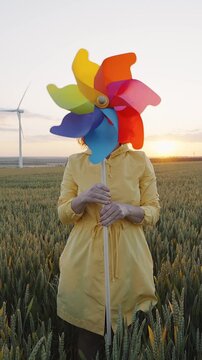 Woman covering face colorful pinwheel wheat field sunset windmill playful childhood freedom concep