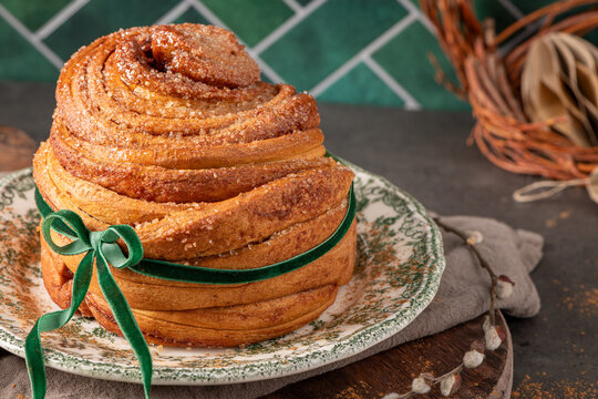 Beautifully baked puff pastry Easter cruffin coated in cinnamon sugar and tied with a green velvet bow on a vintage plate with rustic spring decor