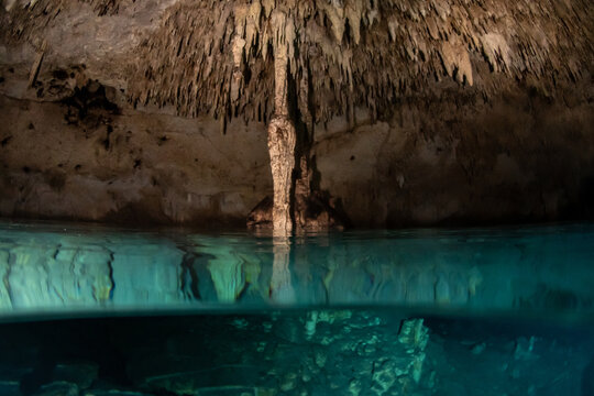Half underwater split view inside a Yucatan cenote air chamber with limestone formations