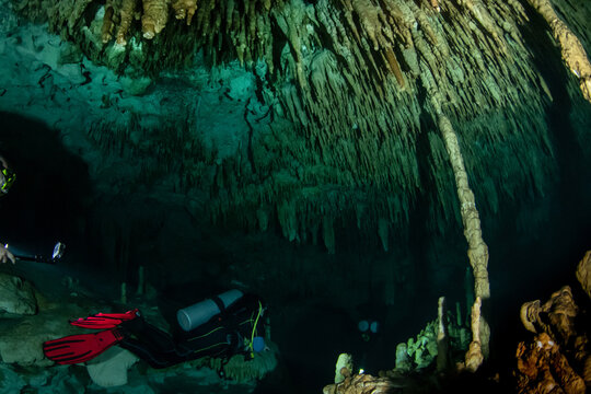 Cave divers entering a hidden cenote underwater cave system in Mexico