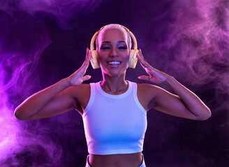 African american model wear headphones enjoy listen music mix. Woman stand at purple studio background in trendy club purple party light with fog. © Mike Orlov
