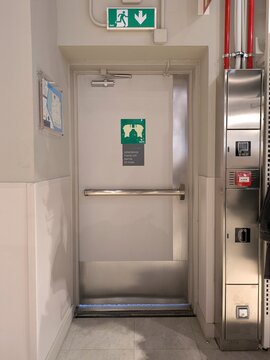 Salida de emergencia con puerta con barra antip&aacute;nico horizontal para abrir empujando, junto a un armario met&aacute;lico con equipo contra incendios, en el interior de un edificio de oficinas 