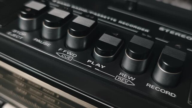 A finger presses the play button on a black vintage cassette recorder to start music, then hits stop. The concept highlights retro audio technology, analog listening, and nostalgia for the 1980s