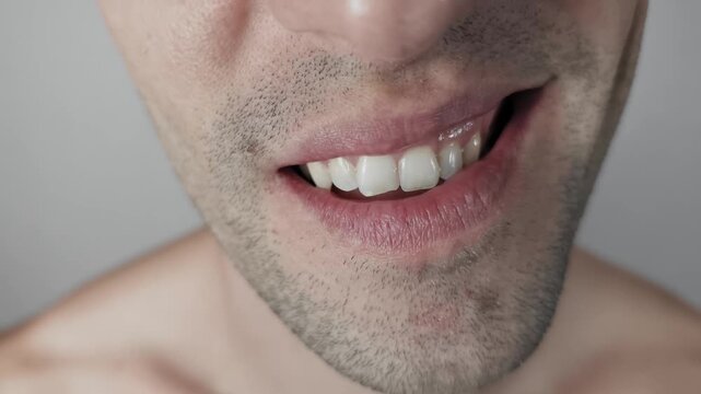 A man's mouth is seen in extreme detail as he curls his lip to reveal white teeth in an angry snarl. Concept of aggression, disgust, and threatening non-verbal communication.