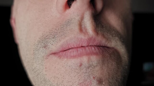 Macro view of a Caucasian man's mouth smiling and showing teeth on a black background. He speaks and expressions shift. This concept highlights dental hygiene and nonverbal communication.