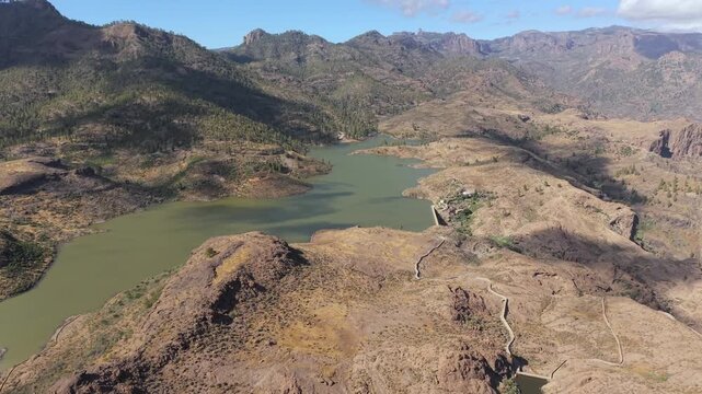 Scenic aerial shot flying over the breathtaking mountainous landscape of Gran Canaria, revealing the Presa de Las Ninas reservoir