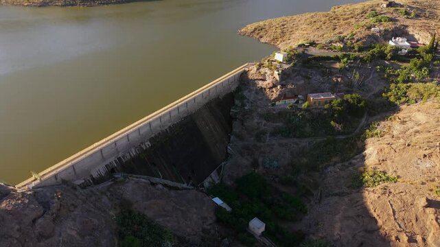 Beautiful aerial view of the Las Ninas Dam at sunset in Gran Canaria, Spain. The concrete structure holds back a large reservoir in a mountain landscape