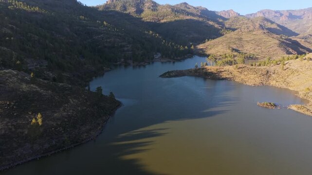 Beautiful aerial view of the Las Ninas dam in Gran Canaria, Canary Islands. The low sun is casting long shadows across the water