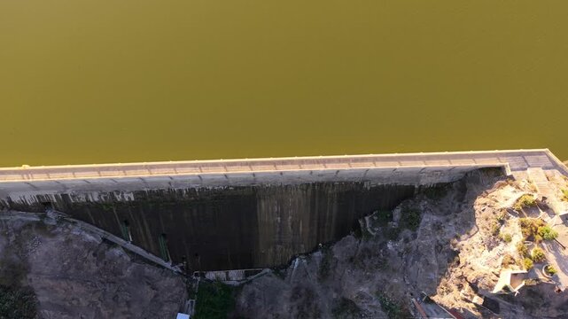 Beautiful aerial view of the Las Ninas Dam in Gran Canaria at sunset. The golden hour light reflects on the tranquil water of the reservoir