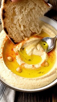 Cinematic View Of Smooth Hummus With Olive Oil Pool Paprika Sprinkle And Pita Bread Being Dipped In Natural Lighting Creamy Middle Eastern Food Commercial