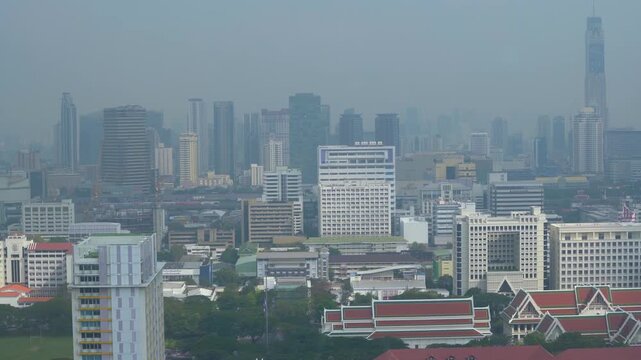 Aerial view of a modern city skyline completely covered in heavy smog and toxic air pollution during the day
