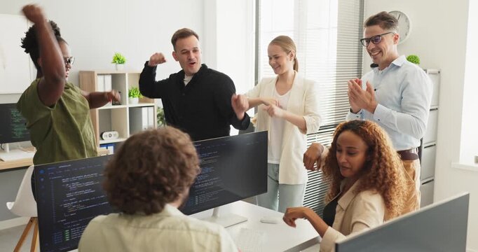 Programmers team celebrate coding success with applause. Developers cheer around monitors with code after releasing an update in a bright office workspace. Strong concept of teamwork success.