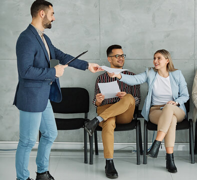 Group of young businss people sitting in chairs and waiting for an interview holding application documents