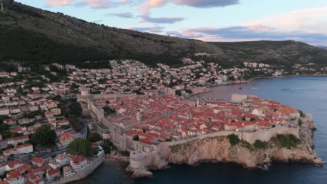 Dubrovnik old town aerial flyover panning above the sea cliffs at dusk