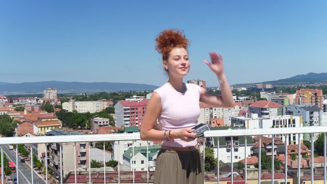 A young woman using a camera and photographing at a building rooftop on a sunny day