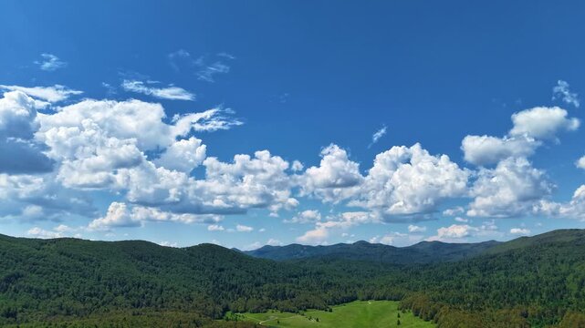 Drone hyperlapse over green mountain valley beneath dramatic summer clouds in Croatia