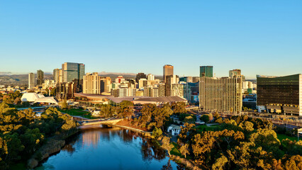 Obraz premium Adelaide City, South Australia – 4K aerial drone footage of CBD skyline, Towers, River Torrens, Convention Centre, Elder Park, city bridges and golden sunset cityscape.