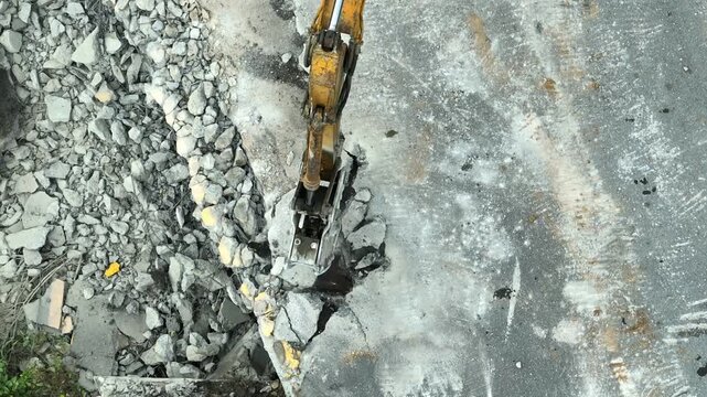 High-angle drone shot of road demolition equipment fracturing concrete foundations, showcasing infrastructure modernization, site preparation, engineering efficiency and city development projects. 4k.