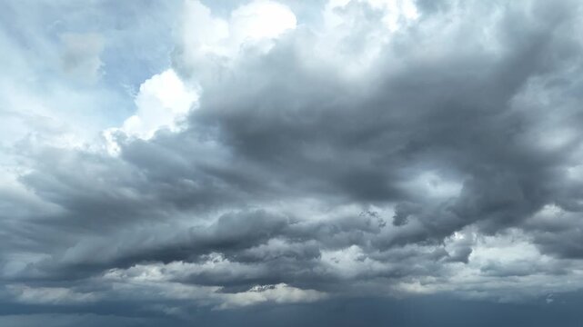 High-altitude drone view of towering storm clouds gathering overhead, representing global warming, severe atmospheric conditions, and the rising intensity of extreme climate patterns. 4k.
