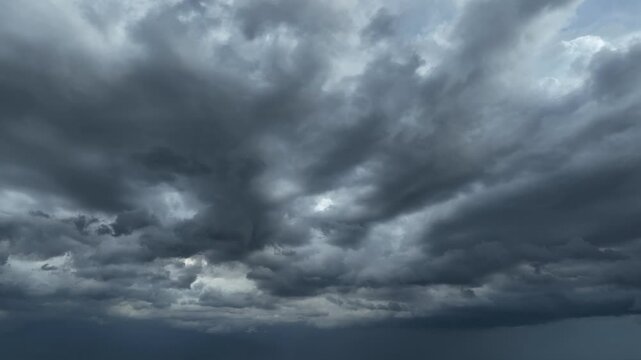 Drone aerial perspective of dense black clouds before a powerful storm, symbolizing climate change, more frequent extreme weather events, and the growing impact of global warming worldwide. 4k.
