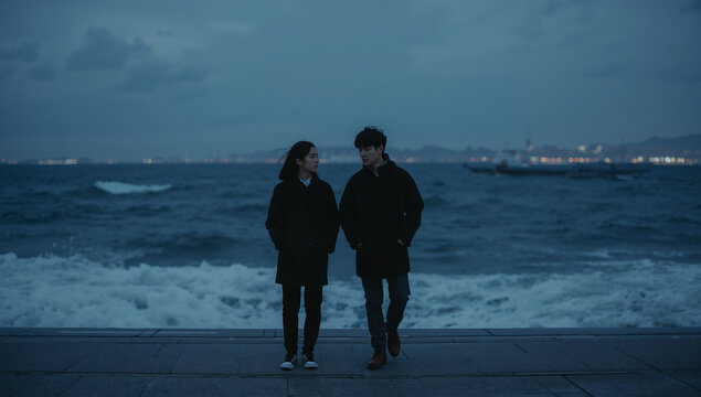 夕暮れの海辺で距離を置いて別れを話す若い男女