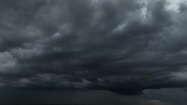Aerial drone view of massive dark storm clouds dominating the sky, highlighting global warming, intensifying extreme weather, and increasing atmospheric instability across the changing climate. 4k.
